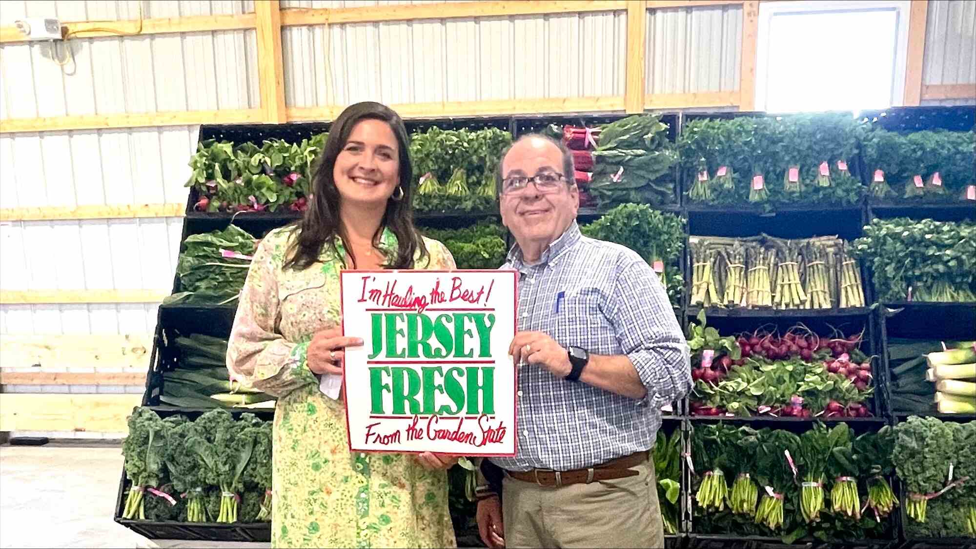 Lods and Romero in front of produce holding a Jersey Fresh sign