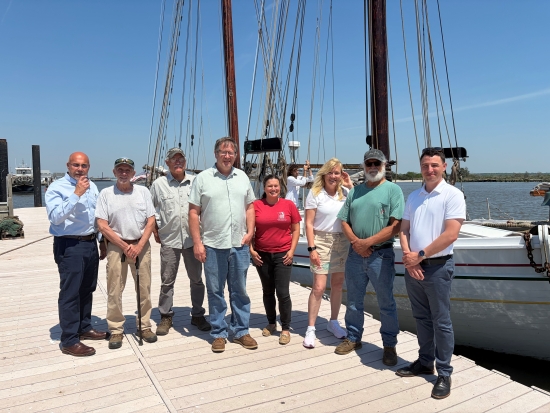 8 people on a dock in front of tall ship